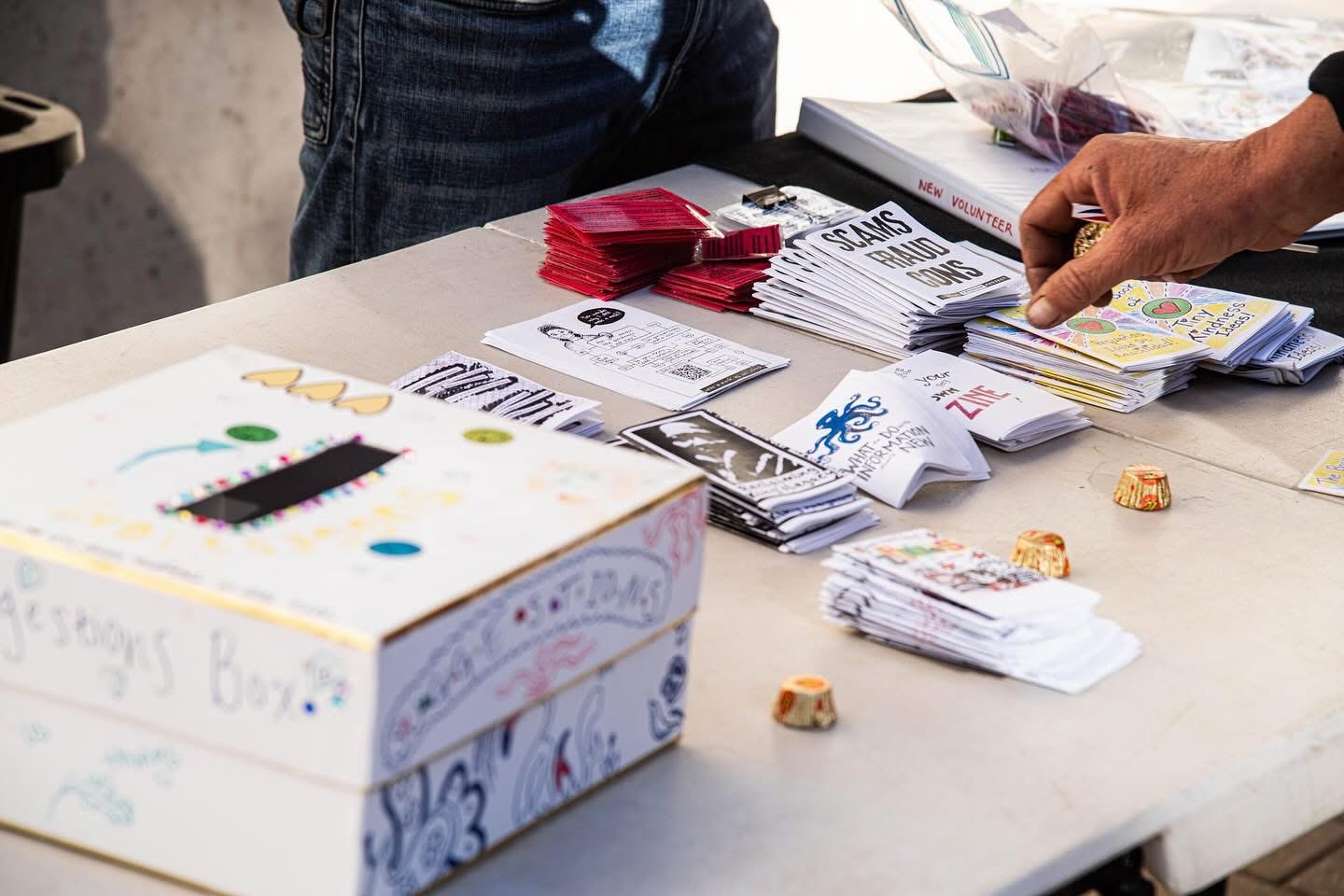 Zines, resource cards and a suggestions box on a table